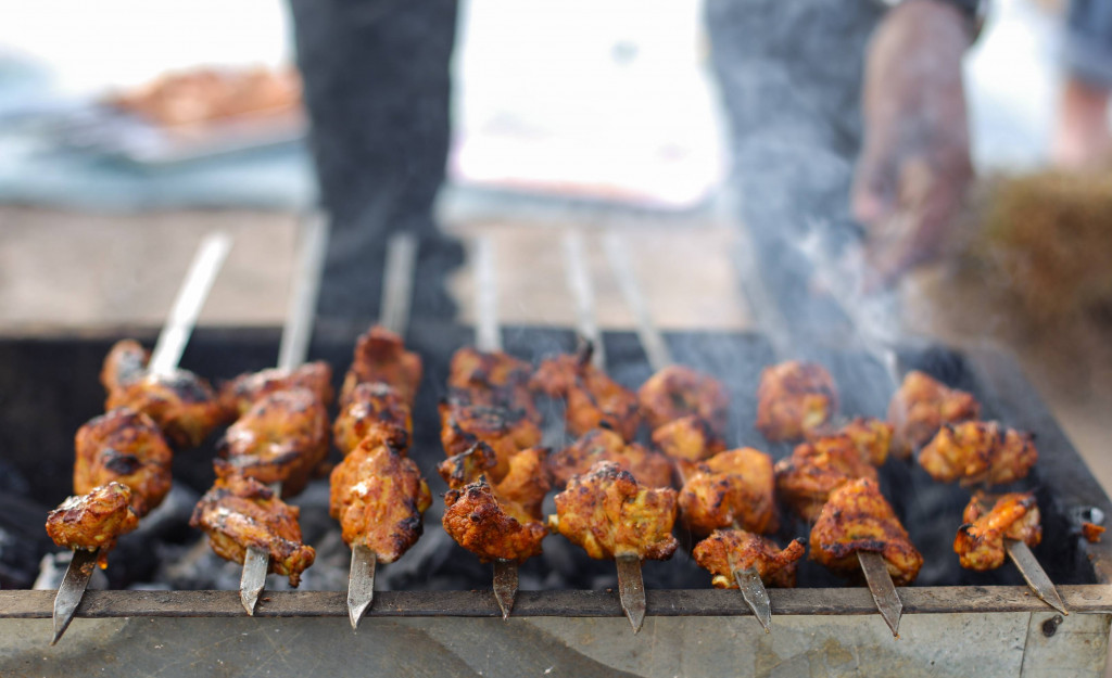 Kebabs arranged on skewers over grill